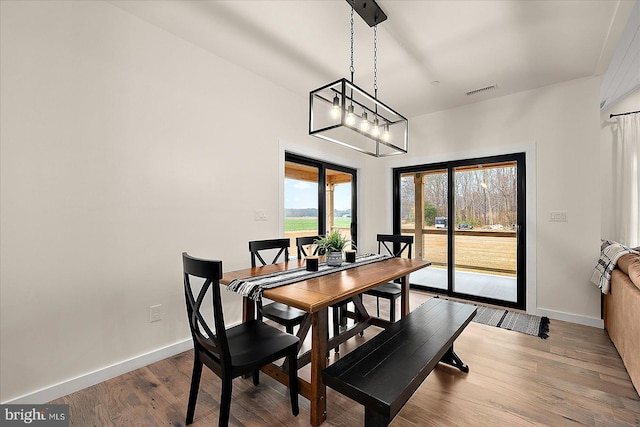 dining space featuring wood-type flooring and a notable chandelier