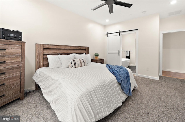 carpeted bedroom featuring ensuite bathroom, a barn door, and ceiling fan