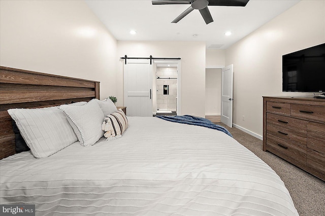 carpeted bedroom with a barn door, ceiling fan, and ensuite bathroom