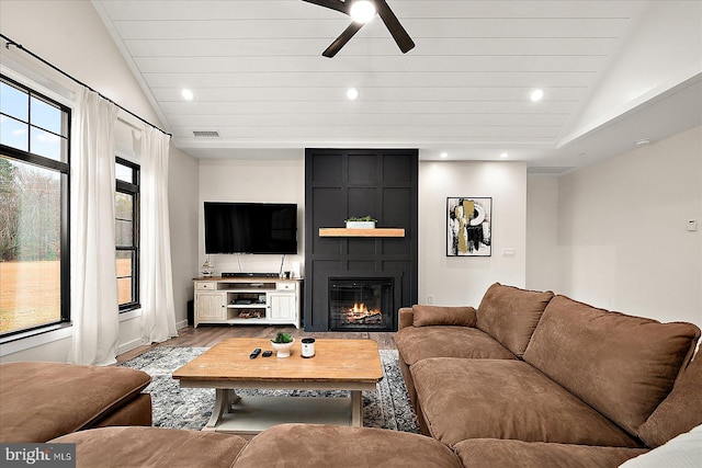 living room featuring a fireplace, light hardwood / wood-style floors, ceiling fan, and lofted ceiling