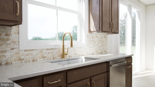 kitchen with decorative backsplash, stainless steel dishwasher, a wealth of natural light, and sink