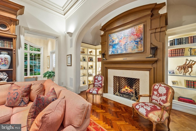 living area with a fireplace, crown molding, built in features, and dark parquet floors