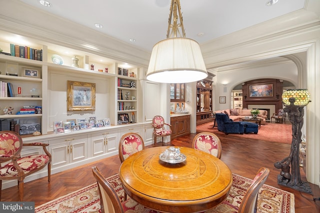 dining space featuring dark parquet flooring, built in features, and ornamental molding