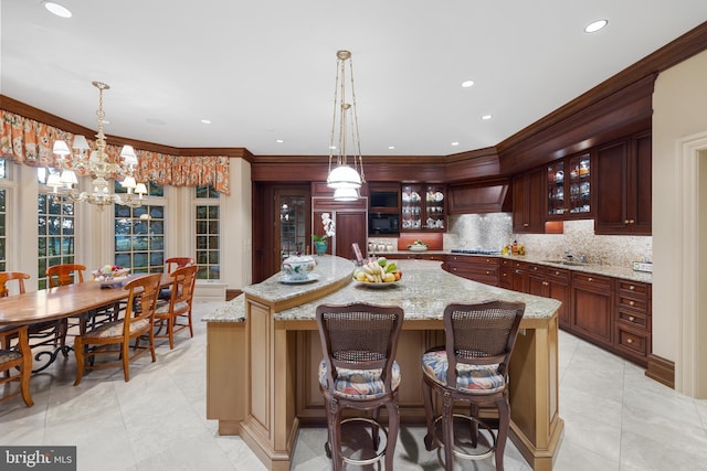 kitchen featuring a kitchen island, sink, ornamental molding, and hanging light fixtures