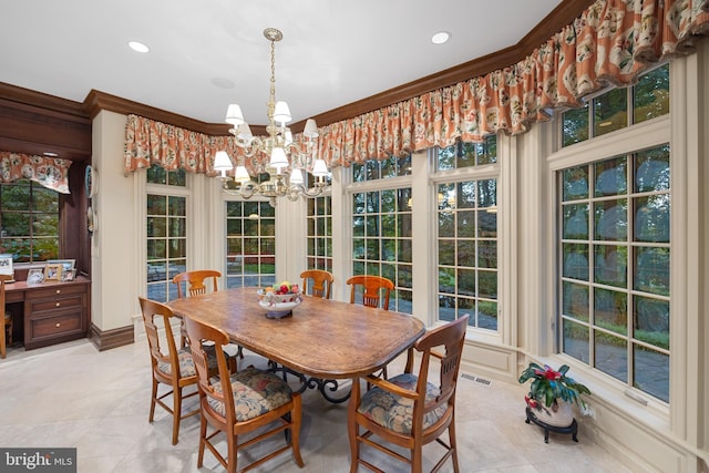 tiled dining space with a healthy amount of sunlight, ornamental molding, and a notable chandelier