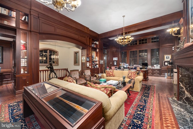 living room featuring dark hardwood / wood-style flooring, wooden walls, and a chandelier