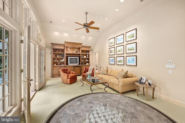 carpeted living room with ceiling fan, french doors, and vaulted ceiling