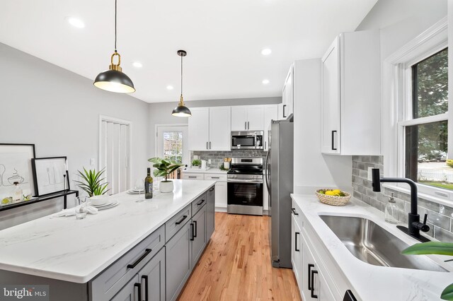 kitchen featuring gray cabinetry, white cabinetry, hanging light fixtures, and appliances with stainless steel finishes