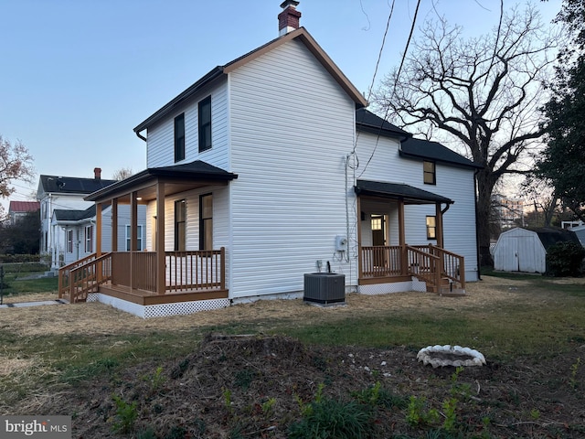 back of house featuring a storage unit, a porch, central air condition unit, and a yard