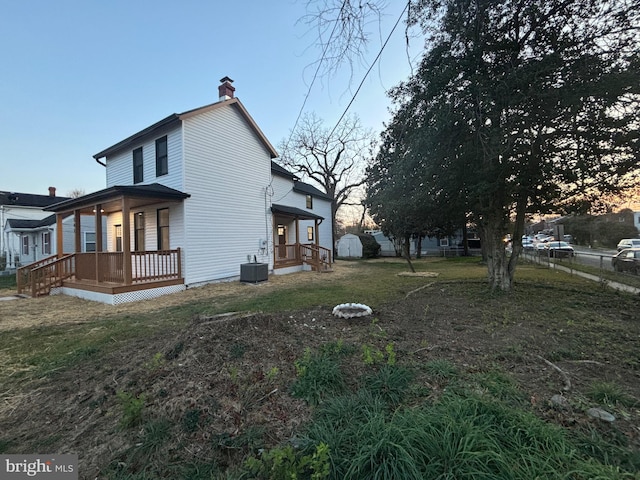 property exterior at dusk featuring covered porch and a lawn