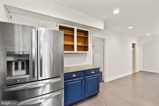 kitchen featuring blue cabinets, light hardwood / wood-style flooring, stainless steel fridge, light stone counters, and white cabinetry