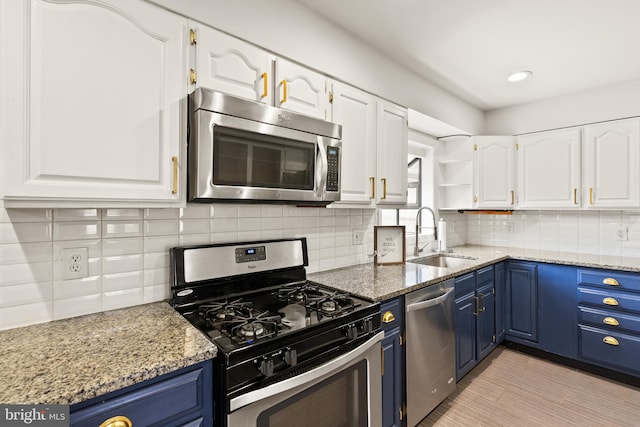 kitchen featuring blue cabinets, white cabinetry, sink, and appliances with stainless steel finishes