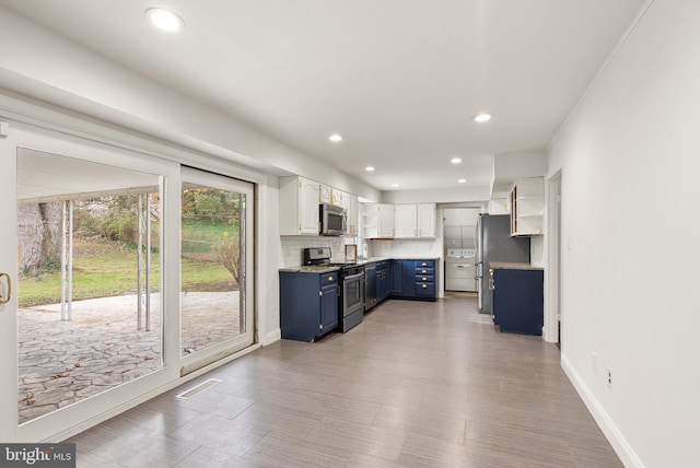 kitchen with backsplash, stainless steel appliances, blue cabinetry, light hardwood / wood-style flooring, and white cabinets