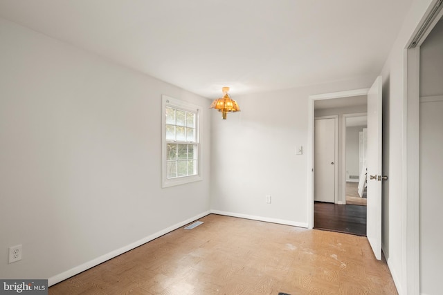 empty room featuring light hardwood / wood-style flooring and a notable chandelier