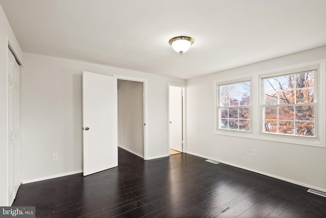 unfurnished bedroom with dark wood-type flooring and a closet