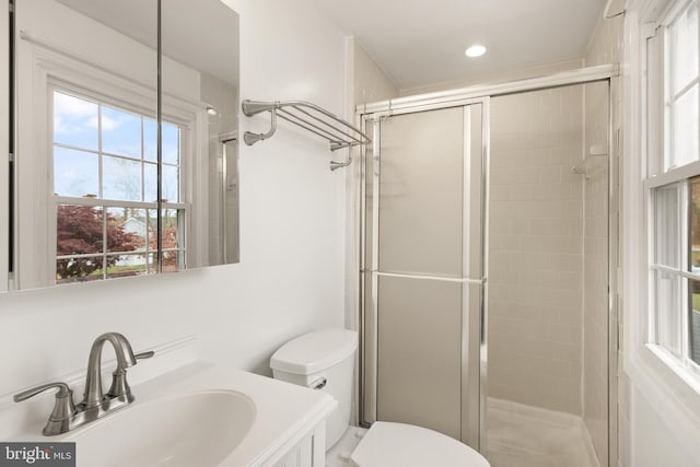 bathroom with a shower with door, vanity, and toilet