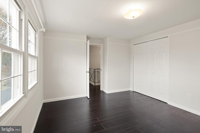 unfurnished bedroom with dark hardwood / wood-style flooring and a closet