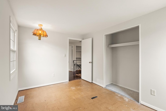 unfurnished bedroom featuring a notable chandelier, light hardwood / wood-style flooring, and a closet