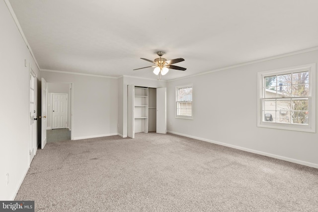 unfurnished bedroom featuring multiple windows, ceiling fan, carpet floors, and ornamental molding