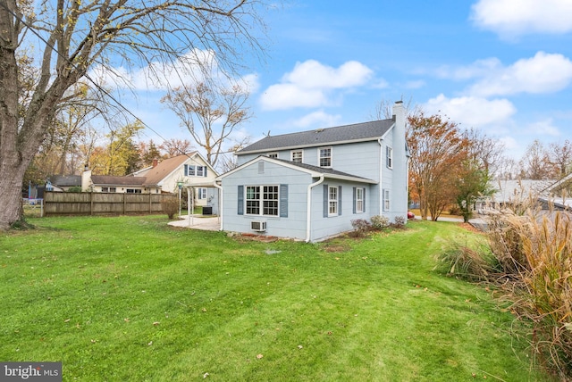 rear view of house featuring a lawn and a patio