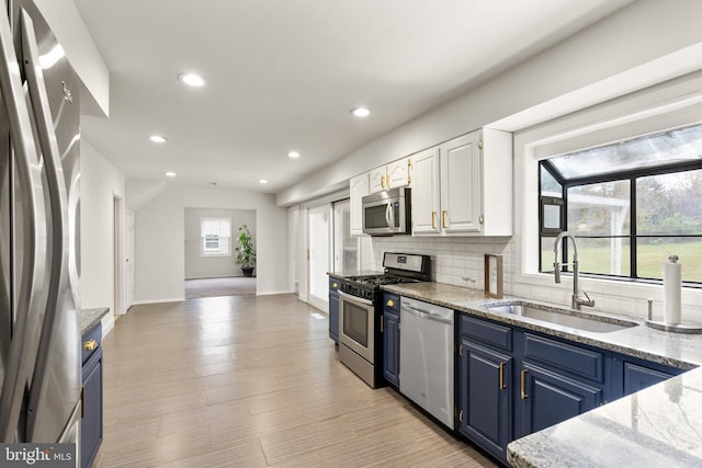 kitchen featuring blue cabinetry, sink, stainless steel appliances, light hardwood / wood-style floors, and white cabinets