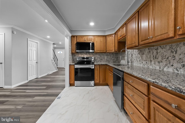 kitchen featuring light stone countertops, sink, stainless steel appliances, and ornamental molding