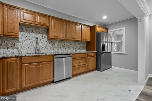 kitchen with backsplash, stainless steel appliances, light stone counters, and sink