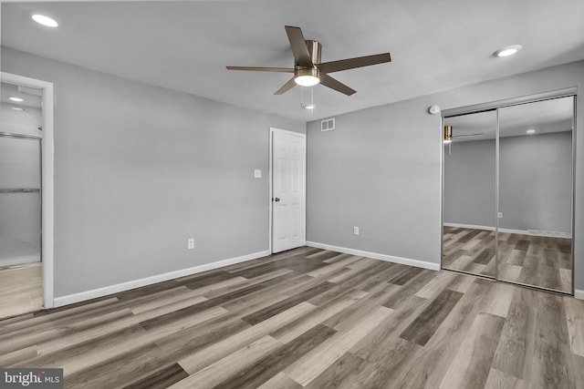 unfurnished bedroom with ceiling fan, a closet, and hardwood / wood-style flooring