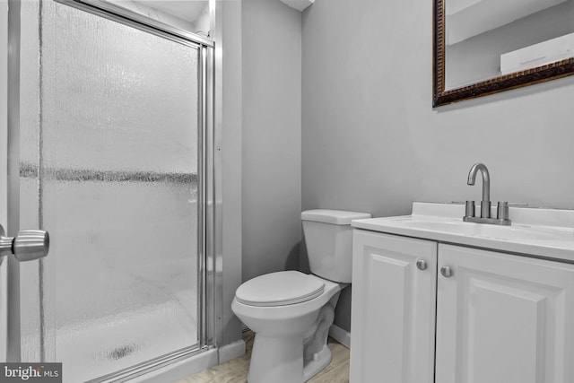 bathroom featuring wood-type flooring, vanity, a shower with shower door, and toilet