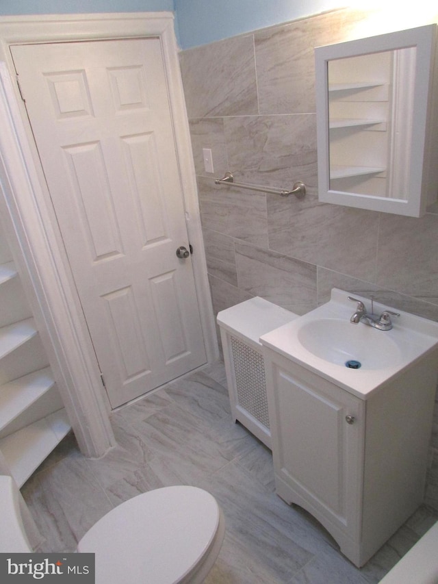 bathroom with toilet, tile walls, and vanity