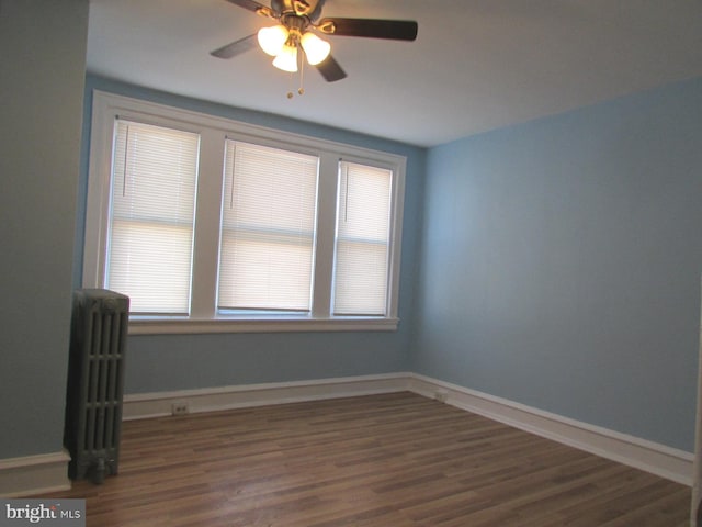 spare room with dark wood-style floors, radiator heating unit, plenty of natural light, and baseboards