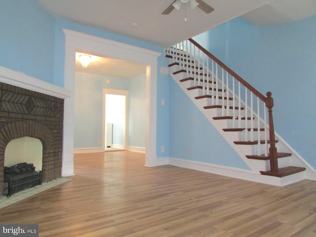 unfurnished living room featuring ceiling fan, wood-type flooring, and a fireplace