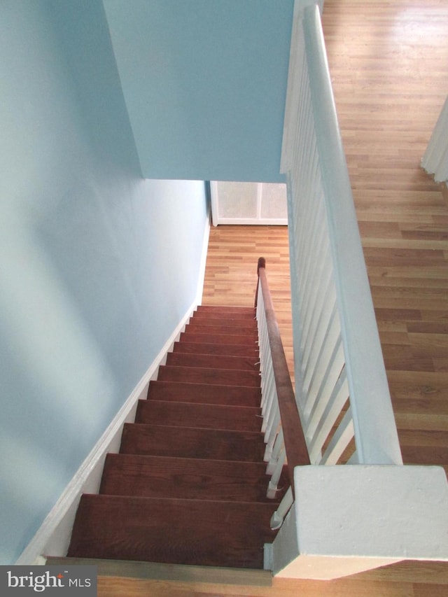 staircase with baseboards and wood finished floors