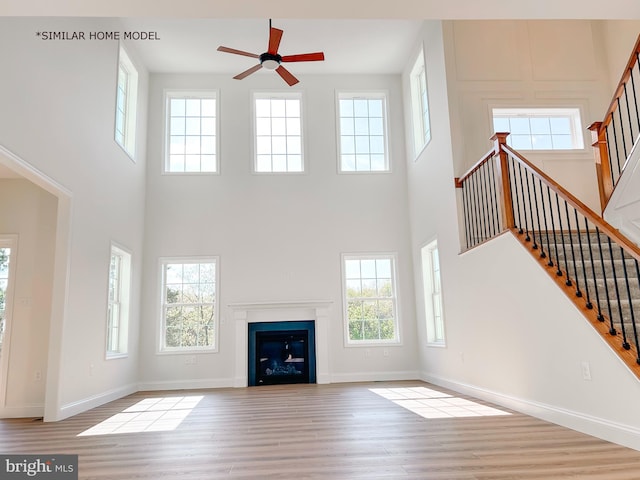 unfurnished living room with a healthy amount of sunlight, light hardwood / wood-style floors, and a high ceiling