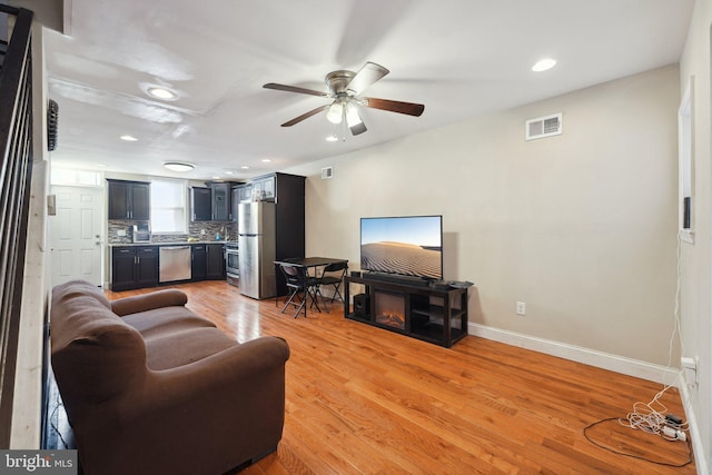 living room featuring ceiling fan and light hardwood / wood-style flooring