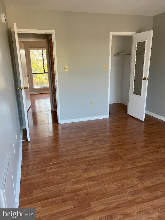 unfurnished bedroom with dark hardwood / wood-style flooring and a closet