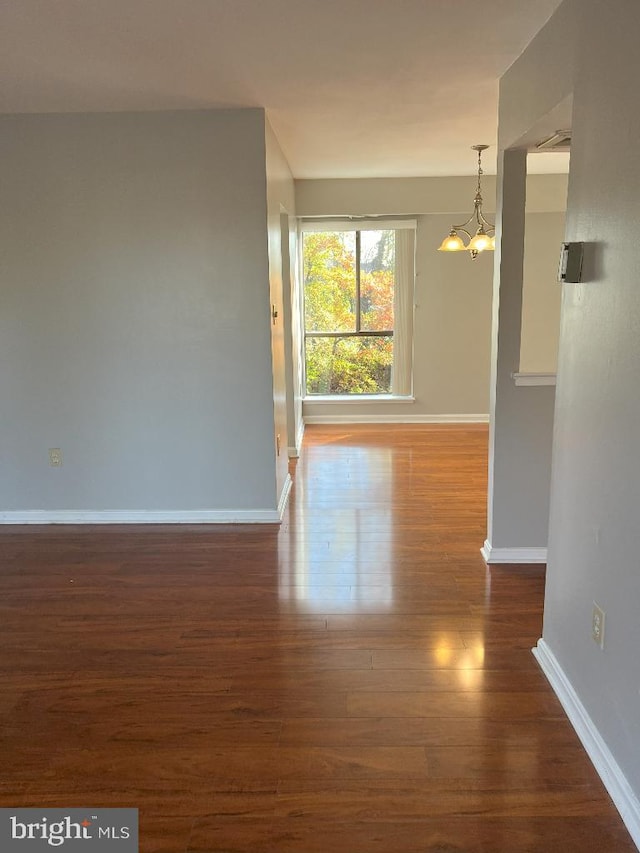 spare room with dark wood-type flooring and a notable chandelier