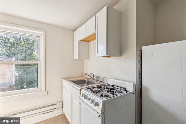 kitchen featuring white appliances, a baseboard heating unit, white cabinets, sink, and light wood-type flooring