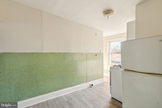 kitchen with washer / dryer, light hardwood / wood-style floors, and white refrigerator