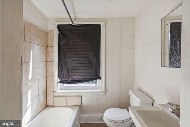 bathroom featuring a tub to relax in, toilet, and sink