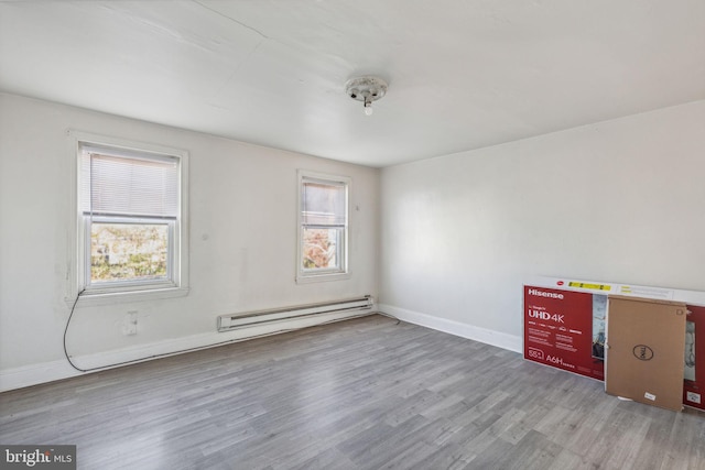 spare room with light hardwood / wood-style floors, a wealth of natural light, and a baseboard heating unit