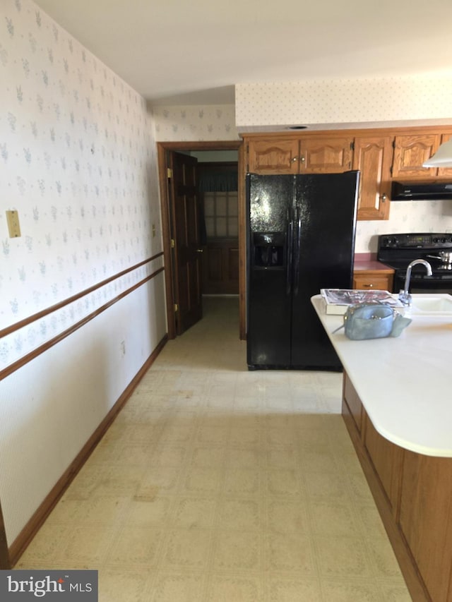 kitchen with sink, wall chimney range hood, and black appliances