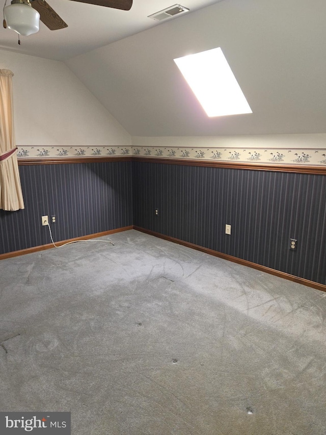 bonus room with lofted ceiling with skylight, carpet floors, and ceiling fan