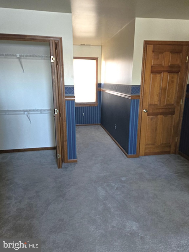 unfurnished bedroom with a closet and dark colored carpet