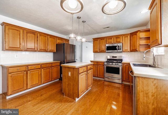 kitchen with dark wood-type flooring, sink, decorative light fixtures, a kitchen island, and stainless steel appliances