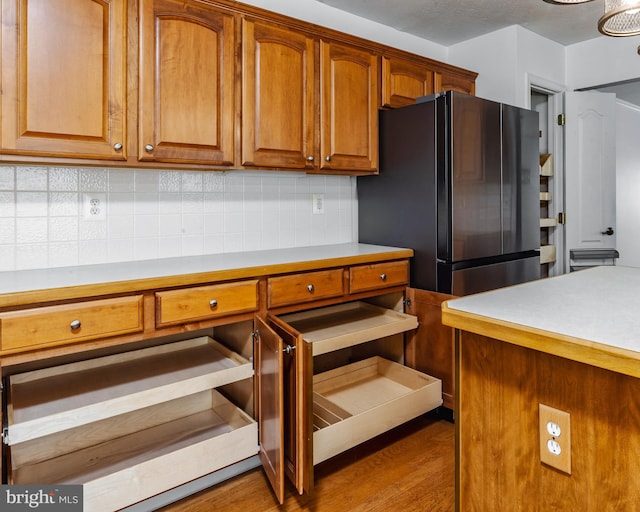 kitchen with decorative backsplash, hardwood / wood-style floors, and stainless steel refrigerator