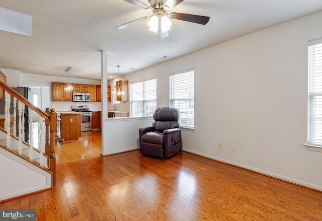 living area featuring ceiling fan, sink, and light hardwood / wood-style floors