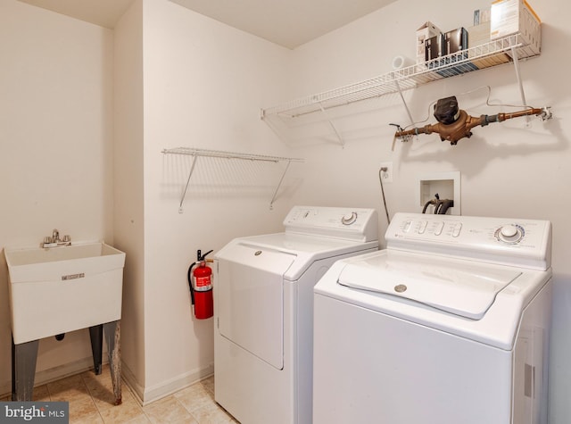 clothes washing area with washing machine and dryer and light tile patterned floors