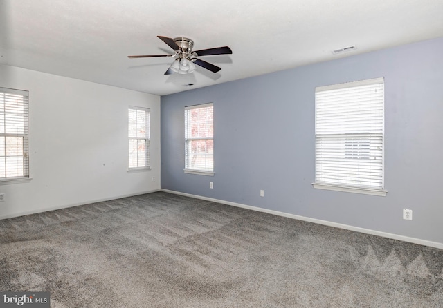 carpeted spare room featuring ceiling fan and a wealth of natural light