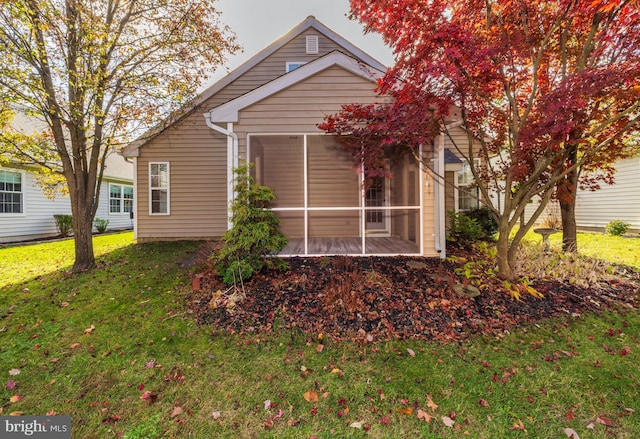 back of property with a lawn and a sunroom